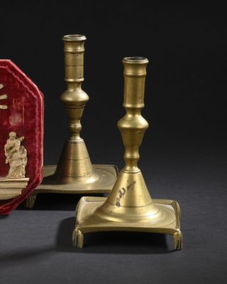 deux bougeoirs en or et une boîte rouge sur laquelle figure une image de Jésus
