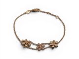 un bracelet en or avec une breloque en forme de fleur suspendue à une chaîne