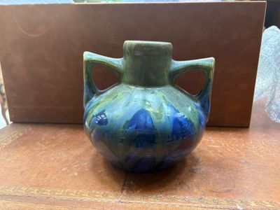 un vase bleu et vert posé sur une table en bois