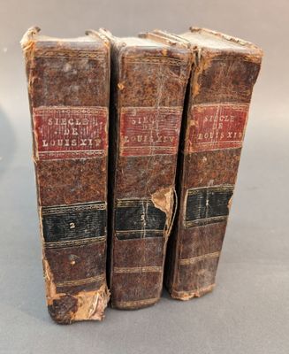 trois vieux livres posés l'un sur l'autre sur une table