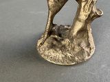a bronze statue of a dog on a tree stump