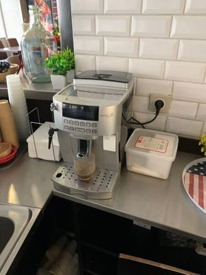 une machine à café posée sur le plan de travail de la cuisine, à côté de l'évier