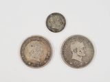 three coins of different sizes and shapes on a white surface