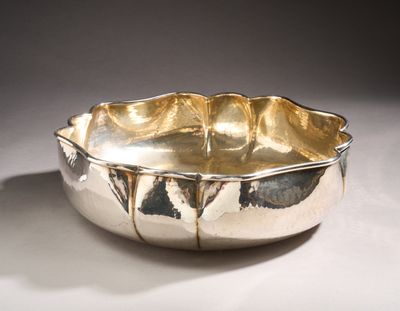 silver plated bowl sitting on top of a white surface