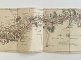 un vieux livre sur lequel figure une carte, posé sur une table