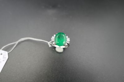 une bague en émeraude et diamant sur une surface noire