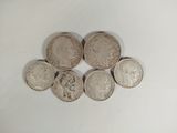 six different british coins sitting on top of each other on a white surface