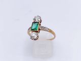 gros plan d'une bague avec une pierre verte et des diamants