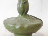 a green vase with a flower in it on a table
