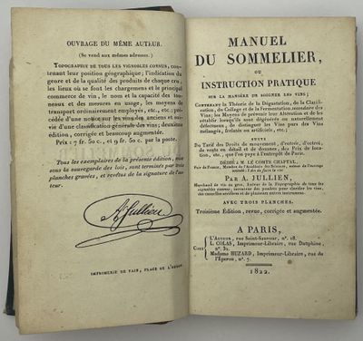 un livre ouvert, sur lequel figure une signature, posé sur une table