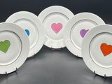 four plates with hearts painted on them sitting on a table