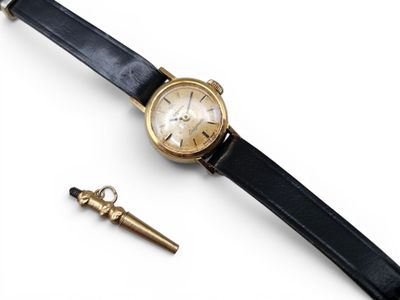 une image représentant une montre en or avec un bracelet en cuir noir et une chaîne de montre en or