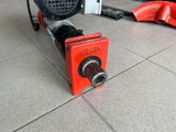 a red pipe cutter on the floor next to a red hose