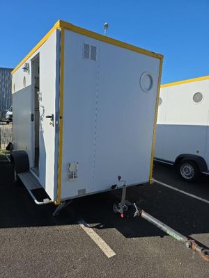une remorque blanche avec des finitions jaunes, garée sur un parking