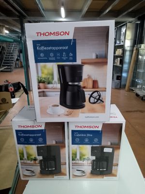 trois cartons contenant des machines à café posés sur une table dans un magasin