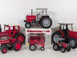 three toy tractors are sitting next to each other on a white surface