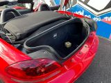 a red sports car with its trunk open in a parking lot