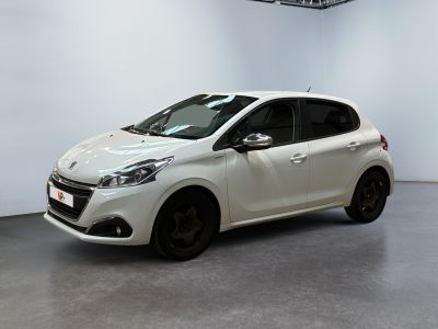 La voiture blanche est garée dans une grande pièce aux murs blancs.