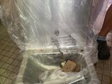 a man standing next to a piece of luggage that is wrapped in plastic
