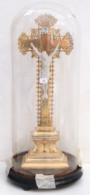 a gold cross under a glass dome on a table