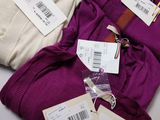 two pairs of purple pants with tags on them sitting next to each other