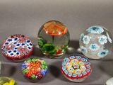 six glass balls with different designs on them sitting on a table