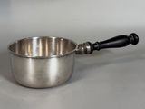 a small metal bowl with a wooden handle on a table