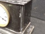 a small black clock sitting on top of a table