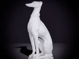 statue d'un lévrier blanc assis sur une surface noire