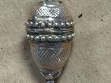 a small silver object with a bell hanging from it ' s side