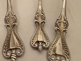 three silver spoons and a fork on a white surface