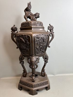 a bronze urn with a bird on top of it