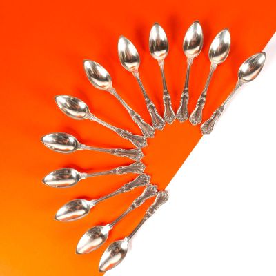 Plusieurs cuillères sont disposées en cercle sur un fond orange.