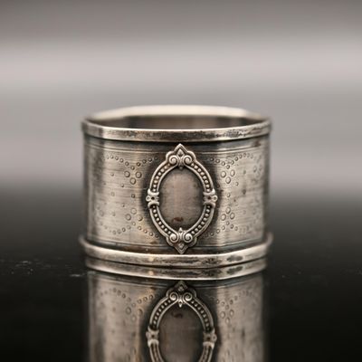 a close up of a silver ring on a table with a reflection