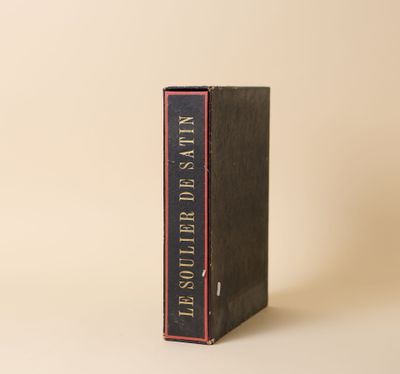 un vieux livre posé sur une table à côté d'un mur blanc