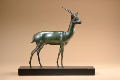 an image of a bronze statue of a gazelle on a wooden base