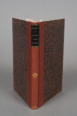 an old book with a red cover sitting on top of a table