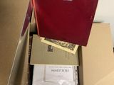 une boîte rouge posée sur une table, contenant des papiers et un dossier