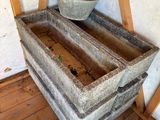 a large stone trough sitting on the floor next to a chair