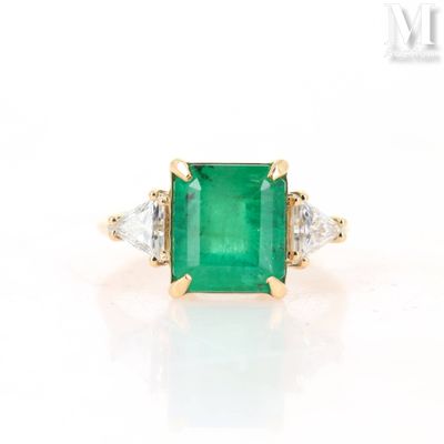 an emerald and diamond three stone ring in yellow gold
