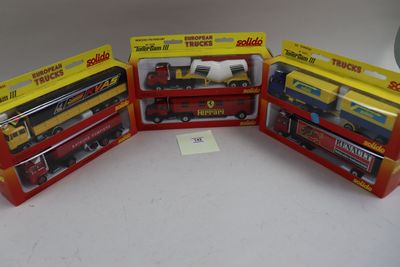 Trois trains miniatures encore dans leur boîte sont posés sur une table