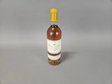 une petite bouteille de vin avec un bouchon jaune posée sur une surface grise