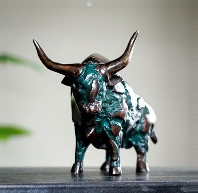 a statue of a bull on a table next to a potted plant