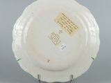 underside view of a white plate with writing on it on a stand