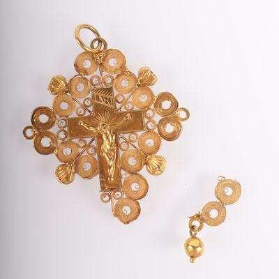 une image représentant une croix en or et une boucle d'oreille sur un fond blanc
