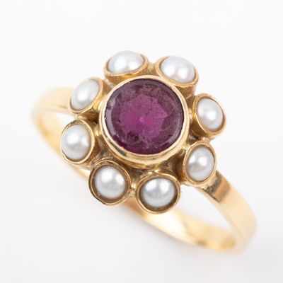 a close up of a gold ring with a pink stone and pearls