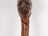 an old wooden walking stick with a carved face on it