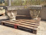 un banc en pierre posé sur une palette devant une clôture