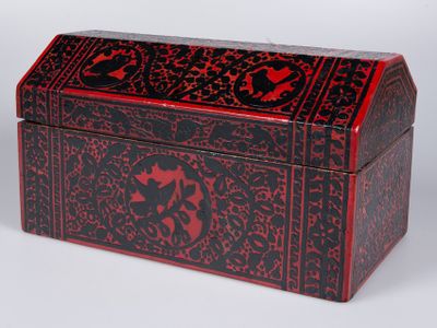 une boîte rouge et noire posée sur une surface blanche