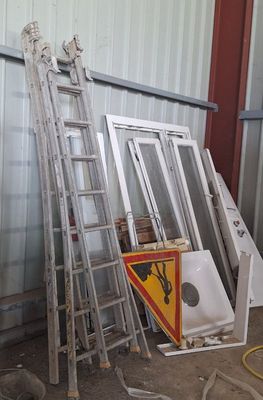 une échelle appuyée contre un mur, à côté d'une pile de fenêtres